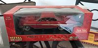 Red 1961 Chevrolet Impala die-cast model car in original Sunstar box showing front and side view through clear plastic window.