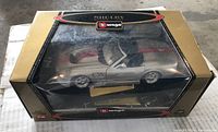 Silver Shelby Series 1 model car in original gold and black Burago Gold Collection box with clear window showing the model inside.
