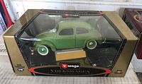 Green 1955 Volkswagen Käfer-Beetle model car in its original clear display box featuring Burago Gold Collection 1:18 scale branding.