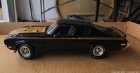 Side view of black Buick model car showing gold stripes on hood and rear, detailed wheels and tires.