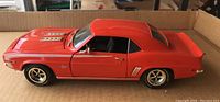 Side view of the red 1969 Chevrolet Camaro SS die-cast model in 1:18 scale, showing detailed wheels, side mirror, and body lines.