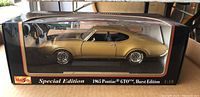 Front-side view of the gold 1965 Pontiac GTO Hurst Edition model car inside its original display box with clear window.