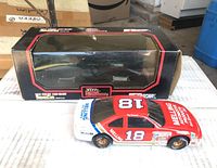 Photo showing die-cast model car outside its display box on a cardboard surface