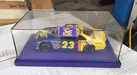 Side view of the Smokin Joes #23 race car model inside clear acrylic display case with purple base.