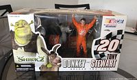 Front of original box showing Tony Stewart in racing suit and Donkey figure from Shrek 2 in clear window packaging with branding