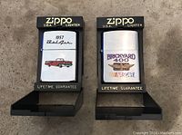 Two Zippo lighter cases displayed side-by-side, left lighter featuring 1957 Bel Air design, right lighter featuring Brickyard 400 NASCAR design.