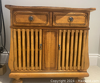 Front view showing two drawers with round metal knobs and three lower cabinet doors with metal handles. Hardwood construction with a natural wood finish.
