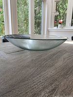 Side angled view showing the shape, depth, and clarity of the clear glass serving bowl on a wooden table.