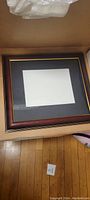 Top view of the diploma frame showing black mat with gold border inside brown wooden frame.