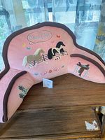 Pink kids reading pillow with embroidered horses and 'Country Girl' text in natural light on wooden surface