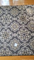 Photo of rug with geometric floral pattern and note for scale or condition