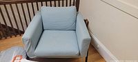 Front view of single blue upholstered side chair with visible stain on left armrest and some marks on seat cushion