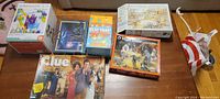 Photo showing 6 games and puzzles including Clue, Beat That, Manzan 2.0 maze puzzle, native American puzzle, and a large 1000-piece jigsaw puzzle box