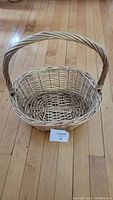 Wicker basket placed on wood floor, showing full basket and handle