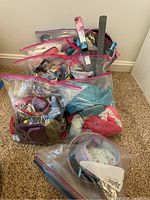 Four clear zip-top bags containing assorted doll accessories plus skis and poles piled