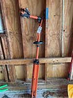Full view of orange bike repair stand set up showing clamp arm and tripod legs