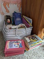 Basket filled with multiple children's books, including some displayed outside the basket showing cover titles and series.