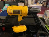 Yellow and black Dewalt DC728 cordless drill shown resting on open black plastic carrying case.