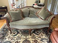 Front view of green upholstered sofa with wood frame and three cushions