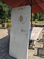White rectangular folding table with significant stains and dirt marks on the surface, showing wear and use.