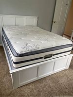 Full assembled bed frame with mattress on carpeted floor against gray wall