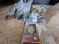 Multiple zip-lock bags containing loose LEGO pieces and original instructions for Harry Potter set 4842 on carpet floor.