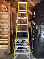 Full view of the Werner 8-foot step ladder showing yellow fiberglass rails and aluminum steps, standing in garage.
