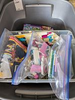 Overview photo of LEGO pieces in multiple clear ziplock bags inside a plastic container, showing various colors and pieces including baseplates and bricks.