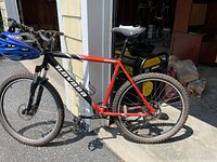 Left-side overview of red Navara bike leaning against garage post
