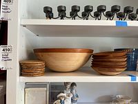 Front view of large wooden salad bowl with six smaller bowls stacked beside it and eight coasters stacked to the left.