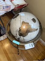 Full view of the decorative standing globe on a metal tripod stand, showing part of the globe and stand design.