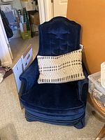 Front view of one blue velvet Victorian chair with tufted back and lumbar pillow