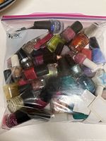 Photo of over 30 assorted used nail polish bottles inside a resealable plastic bag, various colors and finishes visible, along with some nail care tools.