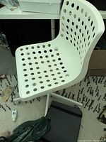 Side angle view of one white Ikea swivel desk chair showing perforated plastic seat and star-shaped leg base with casters.