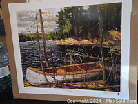 Photo of the Tom Thomson decorative art print titled "The Canoe" showing the boat on a lake surrounded by trees and natural landscape.
