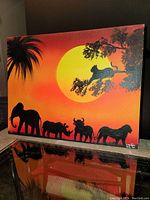 Front view of the African wildlife oil painting on stretched canvas with a bright sunset background and black silhouettes of an elephant, rhinoceros, buffalo, lion, and a leopard on a tree branch. Signed bottom right.