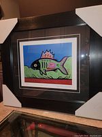 Photo of the professionally framed fine art print by David Morrisseau titled 'Lake Trout', showing the full frame with original corner protectors and clear view of the print colors and details.