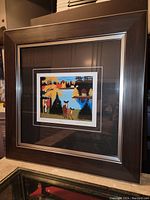 Full view of the professionally framed artwork showing the entire dark wood frame with silver inner trim and the art print of deer by lake surrounded by colorful trees.