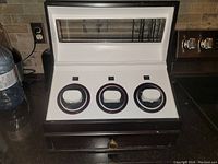Front view of the watch winding display case with the glass top open showing three circular watch winders inside and the drawer below.