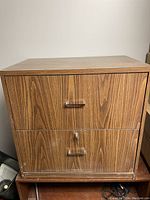 Front view of one wooden filing cabinet showing two drawers with metal handles and wood grain finish