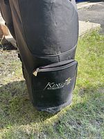 Black King Cobra golf bag with front zippered pocket with King Cobra logo, placed outdoors.
