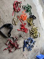 Photo of assorted ratchet and tie down straps in various colors and sizes arranged on a concrete floor.