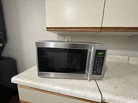 Small Hamilton Beach Microwave on kitchen counter showing full front and right side with digital display