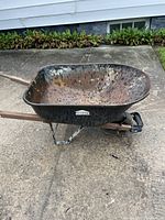 Front and side view of Jobmate metal wheelbarrow showing rusted metal tub and wooden handles.
