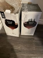 Two original boxes of Urban Barn Pinot Noir wine glasses displayed upright on floor, showing front design and text