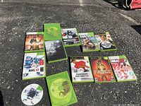 Photo of all game cases and discs laid out on asphalt showing titles and condition.