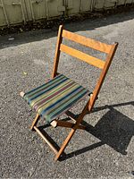 Wooden folding chair standing open outside on pavement showing chair back and seat
