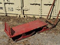 Side angle of antique red wooden sled showing flat bed and metal runners.