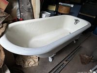 Full view of white enamel-coated claw foot bathtub showing length and interior condition