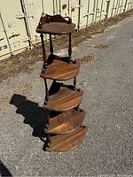 Full height view of the wooden corner whatnot shelf with all five shelves visible, showing the curved triangular shape and turned spindle supports.
